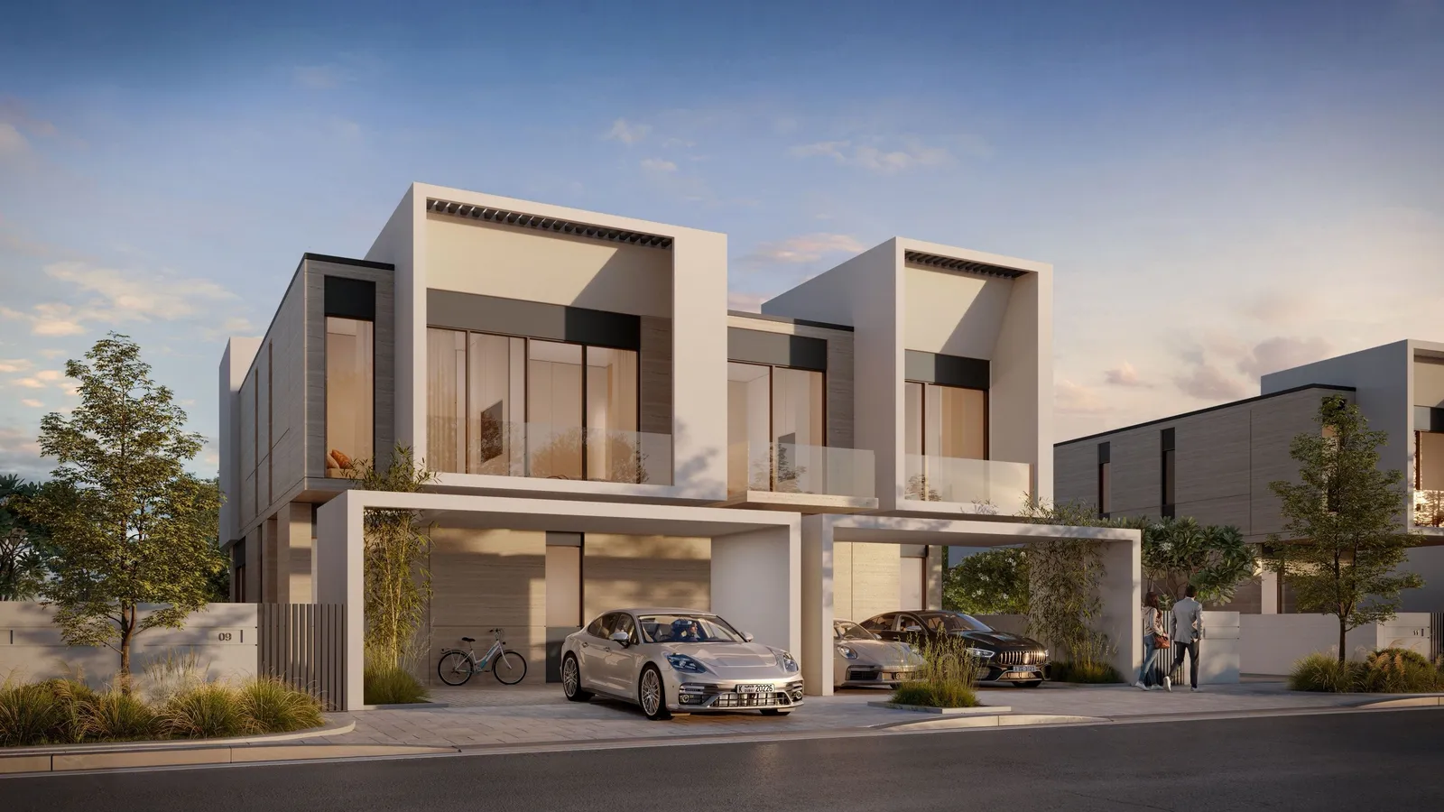 Front of a pair of modern D-Villas at Jumeirah Golf Estates with carports and trees at dusk